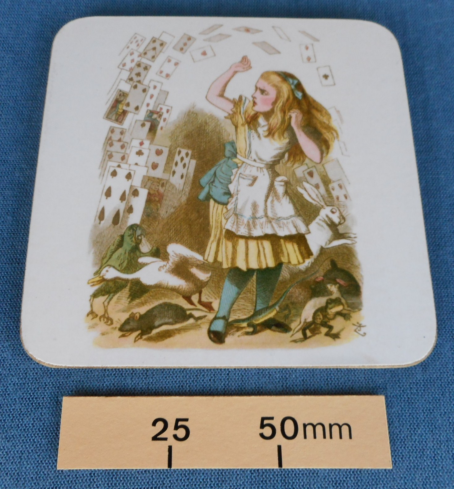 A drinks mat with an image of Alice and the flying cards